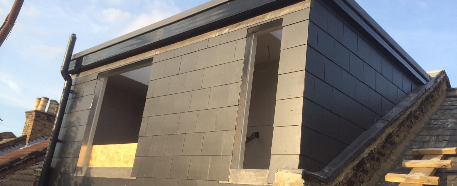 Rooftop extension in progress with modern black cladding, under a clear blue sky reflecting contemporary architecture trends