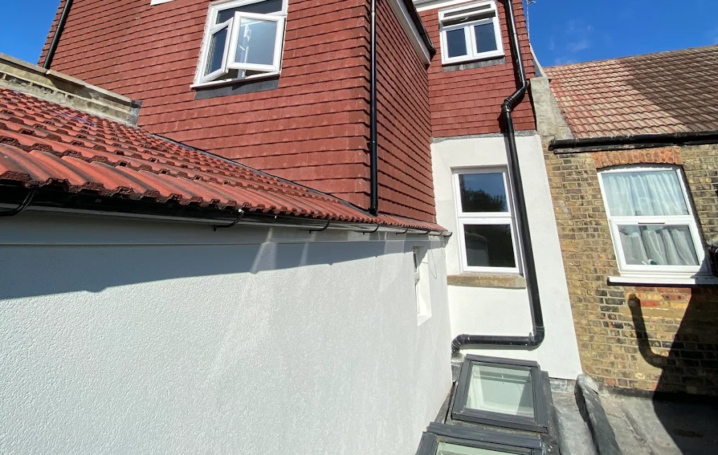 Red brick house extension with new windows and white wall under clear blue sky