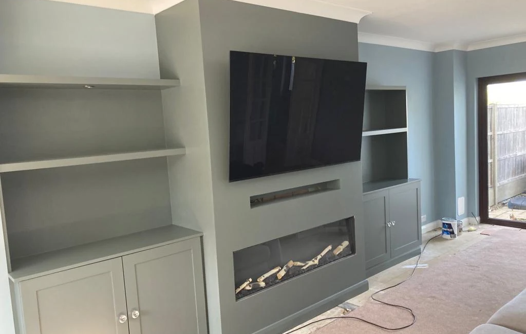 Modern living room with built-in grey cabinetry, flat-screen TV, and a sleek fireplace.
