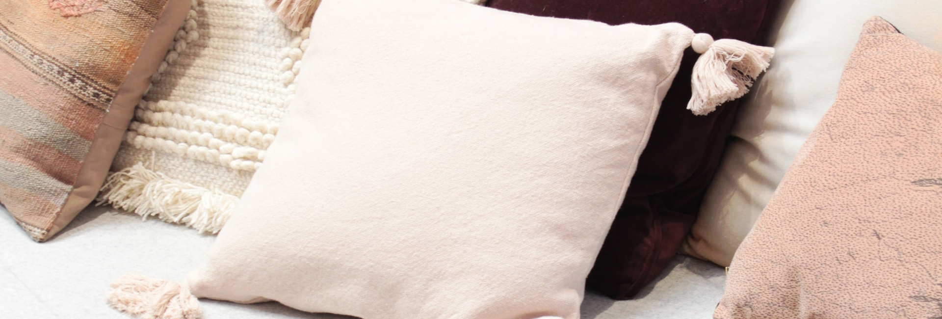 Cosy sofa adorned with a variety of textured cushions in earthy tones and a patterned throw blanket