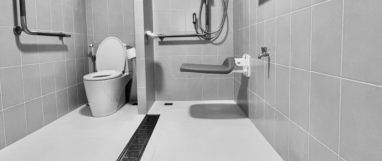 Accessible bathroom with grab bars, shower seat, and tiled floor, designed for disability support and safety