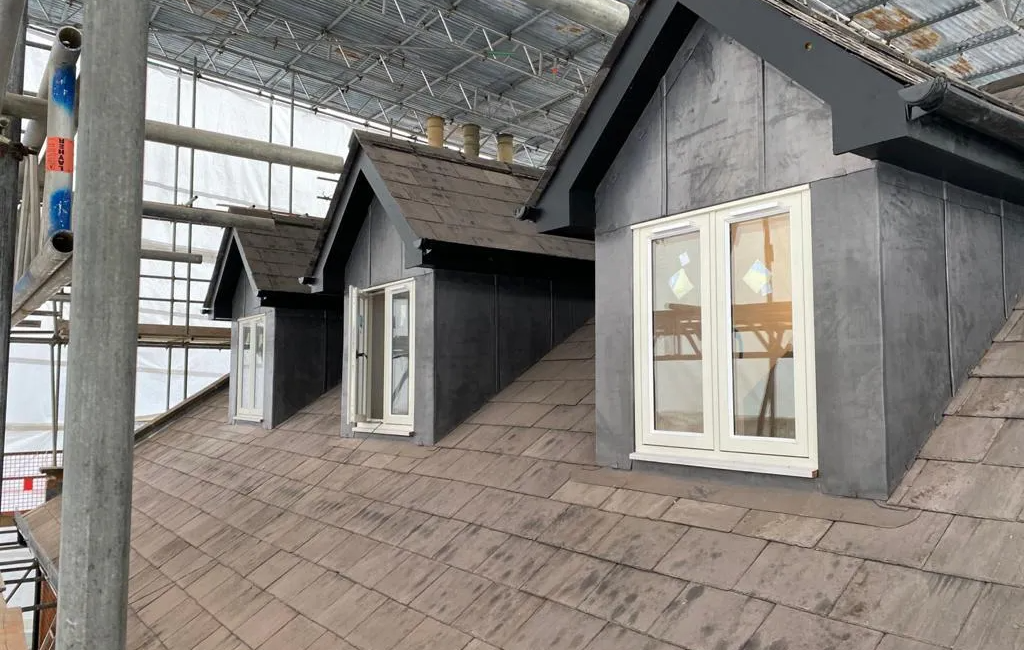 Roof renovation with scaffolding and dormer windows under construction in the UK