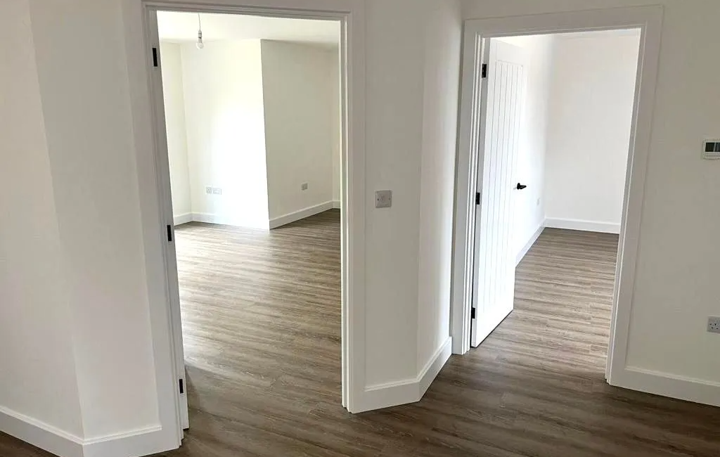 Modern interior with open doors and wood flooring in a bright, empty room layout emphasizing minimalistic design