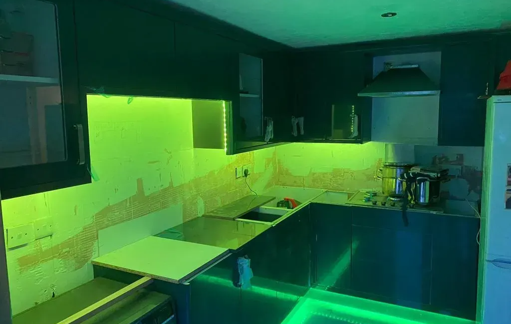 Modern kitchen with dark cabinets and vibrant green LED lighting under cabinets and along the base for a stylish effect