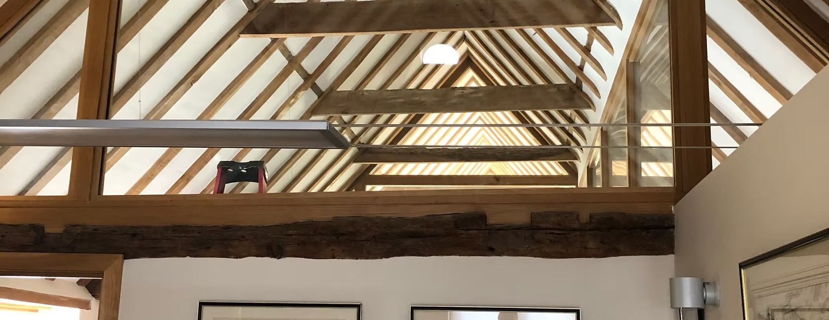 Wooden beams and glass wall in a modern loft office with artwork and natural light filtering through the ceiling