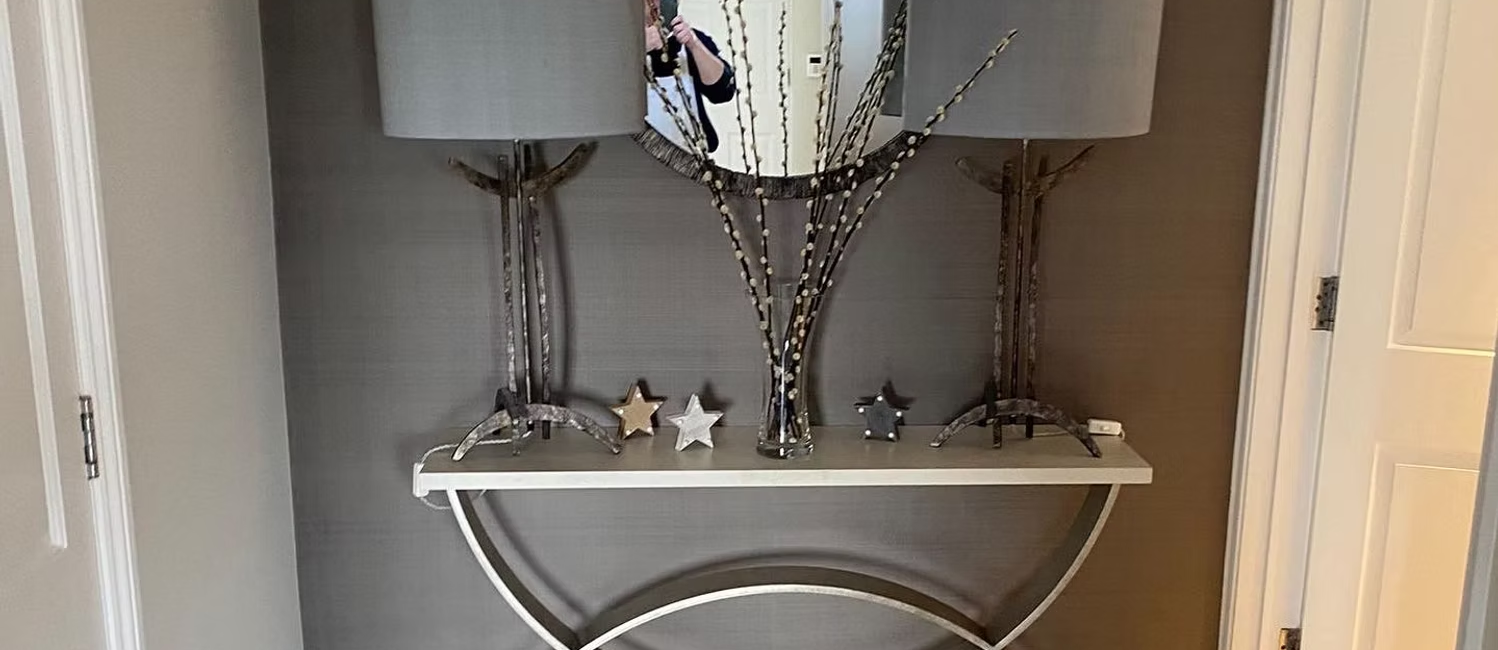 Elegant hallway with a decorative mirror, lamps, and stars on a curved console table in a modern interior setting