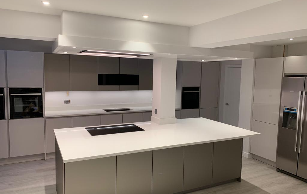 Modern kitchen with sleek grey cabinets, white countertops, and an island, featuring built-in appliances and a fridge