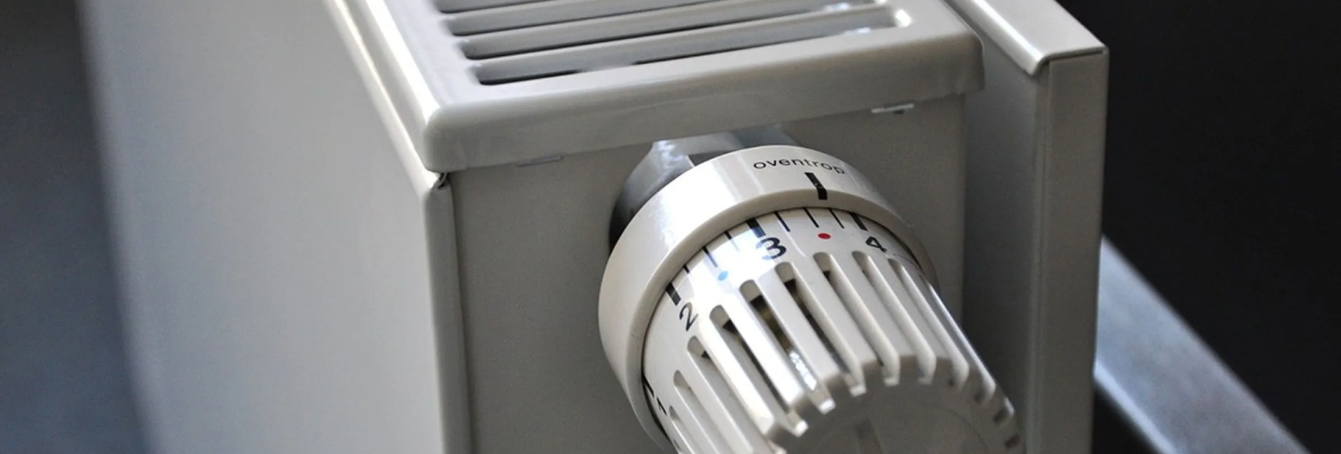Close-up of a white radiator with an adjustable thermostat for temperature control in a modern home setting