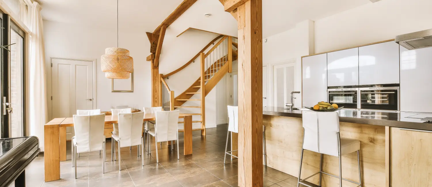 Modern open-plan kitchen and dining area with wooden beams and stylish chairs in a bright, spacious home setting