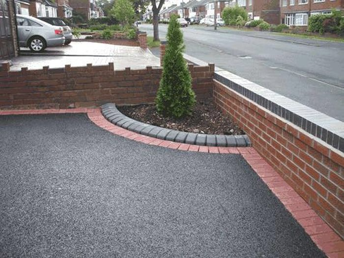 Newly paved driveway with red brick edging and a small landscaped tree bed in a residential neighbourhood