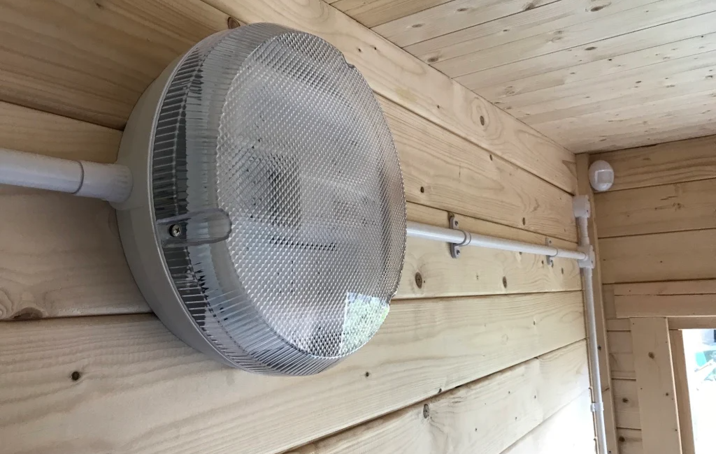 Round wall light fixture on wooden panelled wall in a cosy interior setting