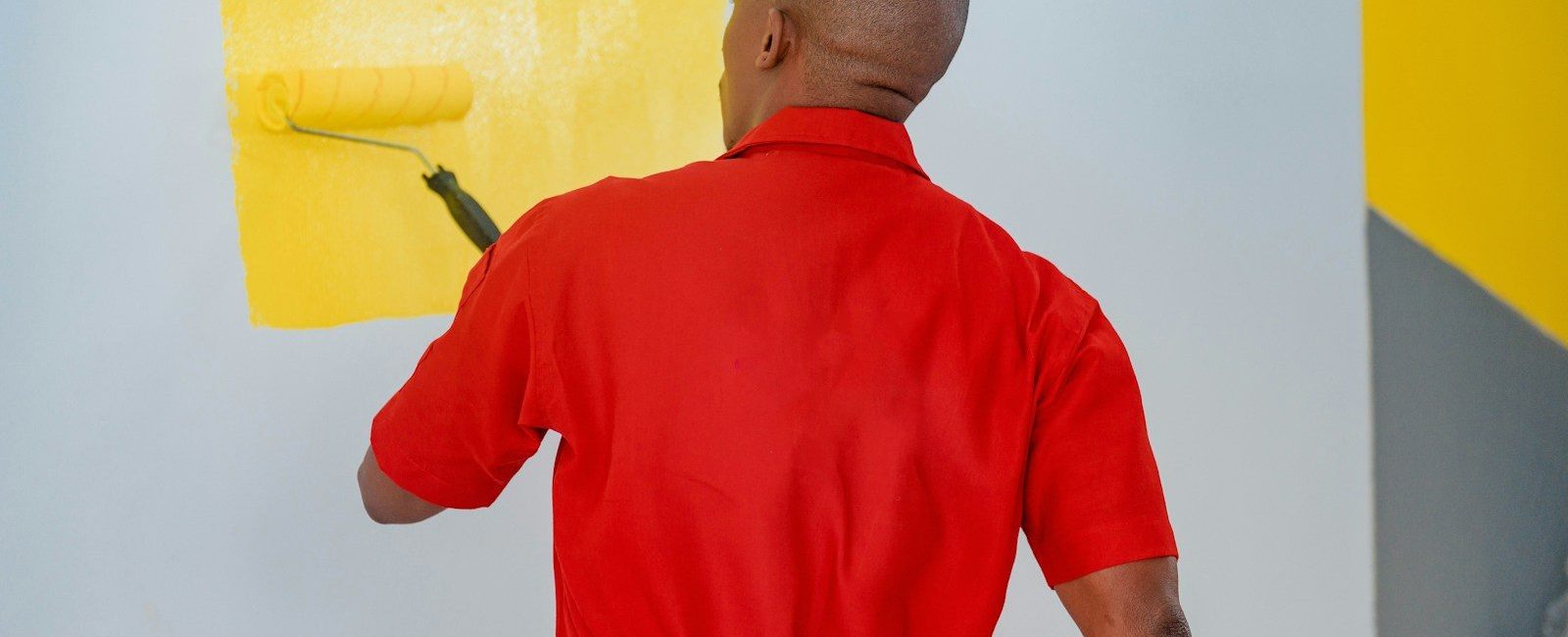 a man painting a wall with yellow paint