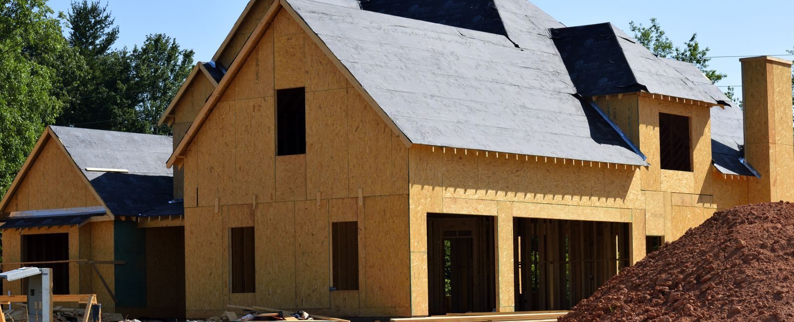 A partially built wooden house under construction, showcasing its progress and design in daylight.