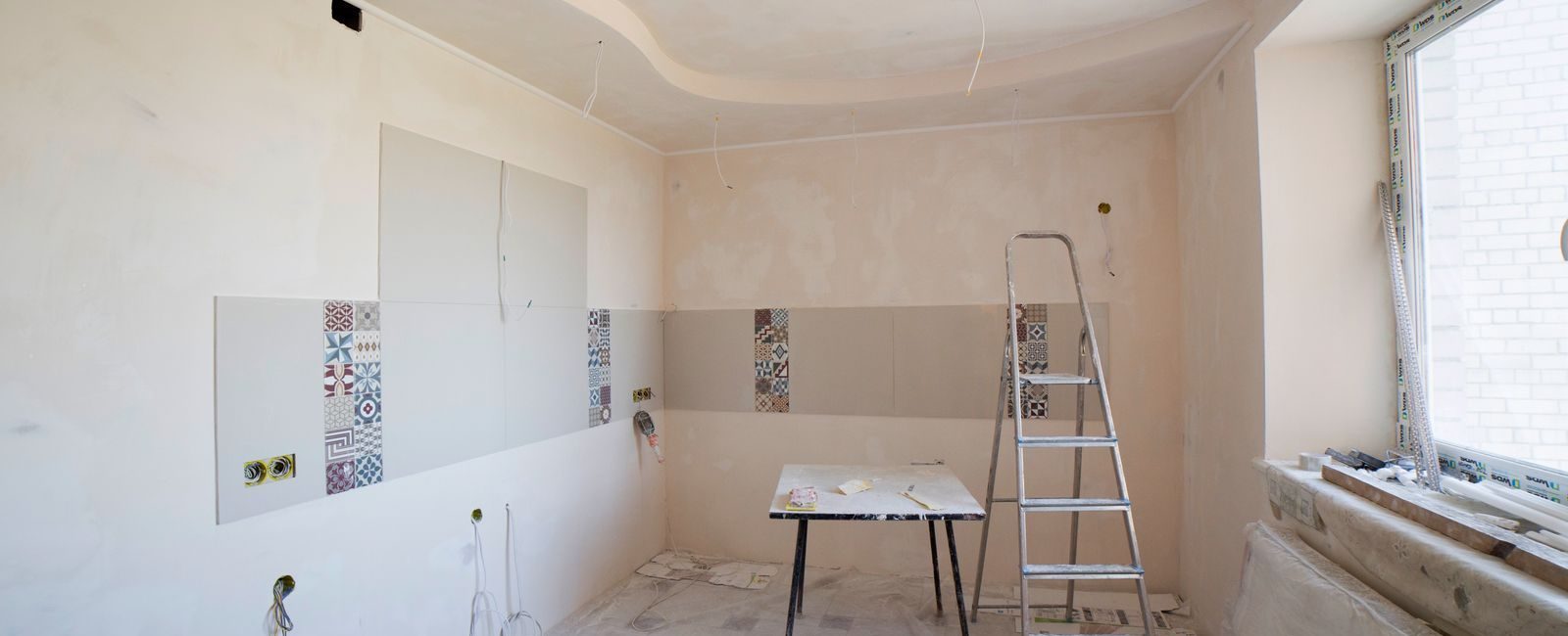 Spacious kitchen under renovation with ladder and tools, showcasing a fresh new design.