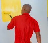 a man painting a wall with yellow paint