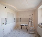 Spacious kitchen under renovation with ladder and tools, showcasing a fresh new design.