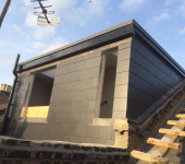 Rooftop extension in progress with modern black cladding, under a clear blue sky reflecting contemporary architecture trends