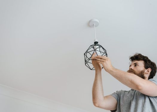 Man installing a modern geometric light fixture on ceiling in a home setting