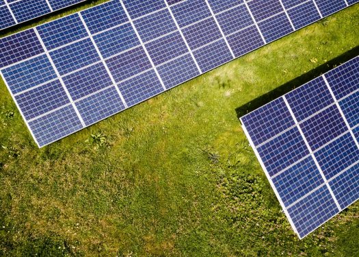 Aerial view of solar panels on lush green grass, showcasing renewable energy technology in a natural setting