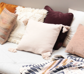 Cosy sofa adorned with a variety of textured cushions in earthy tones and a patterned throw blanket