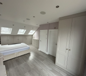 Spacious attic bedroom with skylights, modern cabinetry, and neutral tones, featuring a comfortable double bed