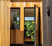 Modern garden room exterior with open door revealing green living wall inside