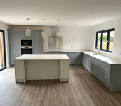 Modern kitchen with grey cabinets, central island, pendant lights, and large windows for natural light