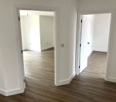 Modern interior with open doors and wood flooring in a bright, empty room layout emphasizing minimalistic design