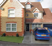Two-storey brick house with driveway, blue car, and skip bin in front garden under cloudy sky