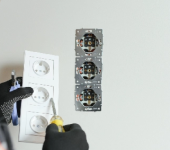 Electrician installing triple power sockets on a wall using tools