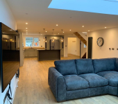 Modern open-plan living room with grey sofa, wooden flooring, and stylish kitchen island with pendant lighting