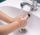 Hands washing with soap under running water in a white sink promoting hygiene and cleanliness