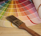 Paintbrush on a wooden table with a vibrant paint colour wheel and roller for home decor and interior design inspiration