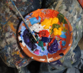 A vibrant palette with mixed acrylic paints on a splattered artist's lap, showcasing creative expression and artistry