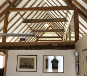 Wooden beams and glass wall in a modern loft office with artwork and natural light filtering through the ceiling