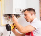 Technician inspecting a boiler unit with a flashlight, ensuring proper maintenance and functionality in home setting
