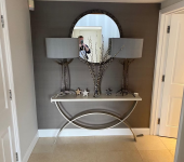 Elegant hallway with a decorative mirror, lamps, and stars on a curved console table in a modern interior setting