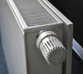 Close-up of a white radiator with an adjustable thermostat for temperature control in a modern home setting