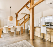 Modern open-plan kitchen and dining area with wooden beams and stylish chairs in a bright, spacious home setting